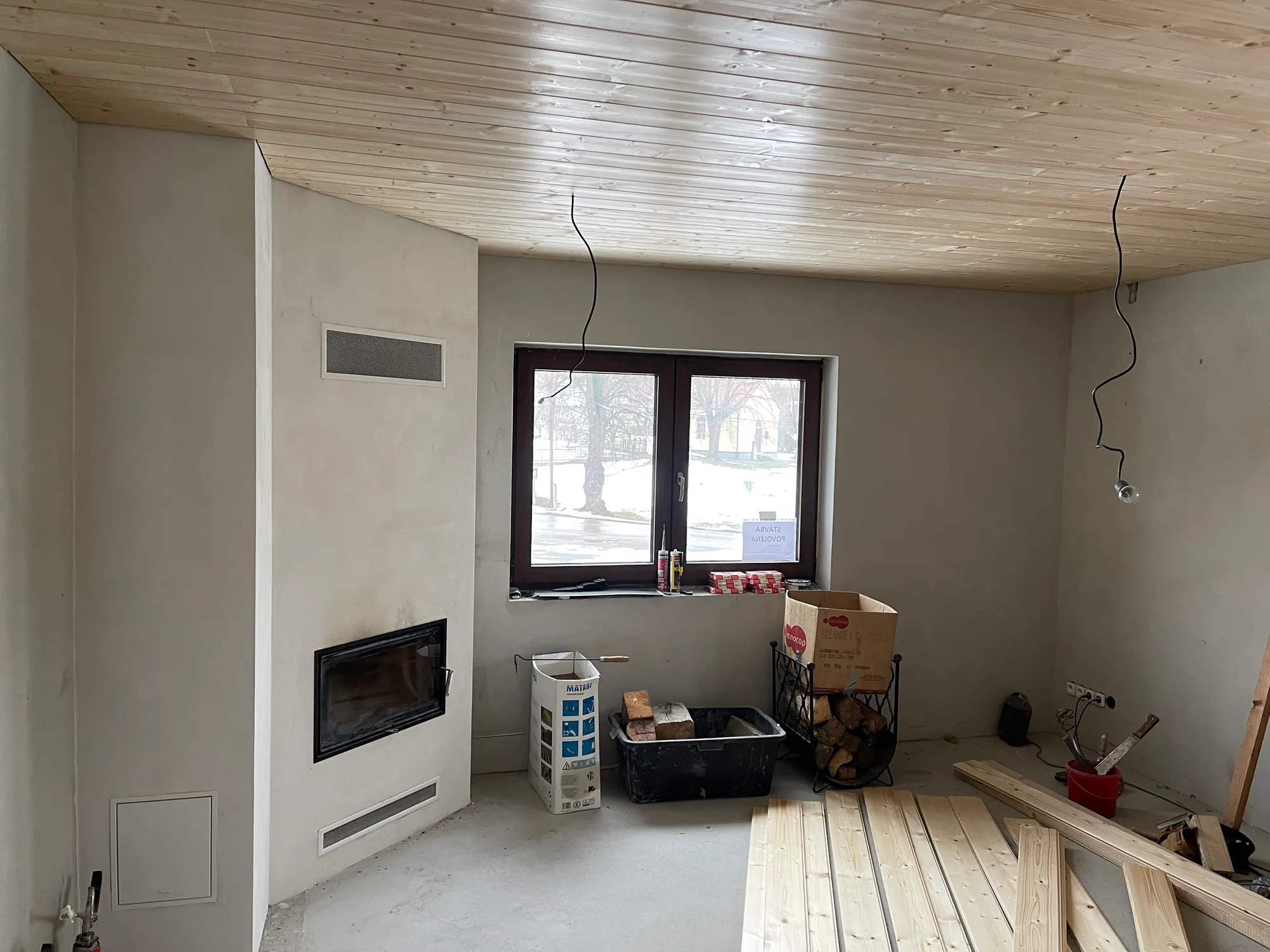 Dokončený interiér s krbem a dřevěným podhledem